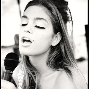 Cindy Crawford Singing Country Western in Cheyenne Wyoming. 1989 by Arthur elgort, the model in a pailette top singing into a microphoen, eyes closed