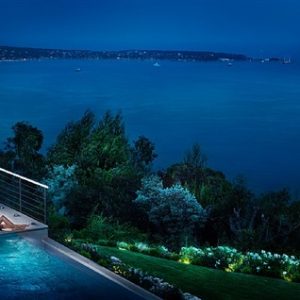 Dreaming of you by David Drebin, model in black dress lying next to apool, the ocean in the background