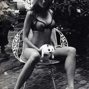 Bunny Brenda Schad by Sante D'Orazio, model in transparent dessous sitting on a white ironcast chair in a garden, holding a white bunny