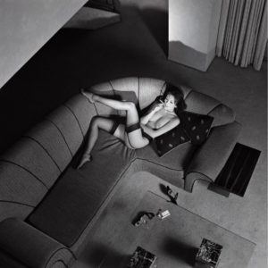 Petra smoking a cigarette by Guido Argentini, model in black stockings lying on a sofa and smoking