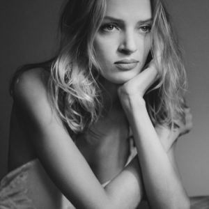 Uma Thurman - NYC 1993 by Albert Watson, black and white portrait of the actress in a white neglige, head in her hand