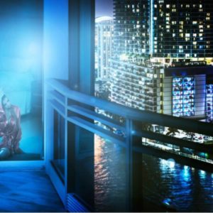Midnight story by David Drebin, model sitting in a red dress by the window, outside a city by night