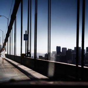 Running the bride by david drebin, model in white dress running over the san francisco bay bridge, the city in the backgrond