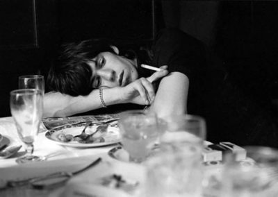 Keith Richards by Terry O'Neill, the musician leaning on a set table, smoking