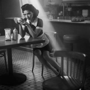 Adriana Lima by Vincent Peters, the model in waitress attire and a cup of coffee sitting in a diner