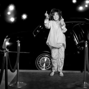 Elisabeth Taylor by Timothy White, the actress in white on a red carpet setting, showing her middle fingers to the camera