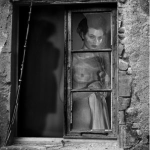 Moa by Vincent Peters, nude model with cord phone looking through an old window