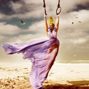 Beach by Kristian Schuller, Model in purple dress and yellow headpiece on rings at the beach