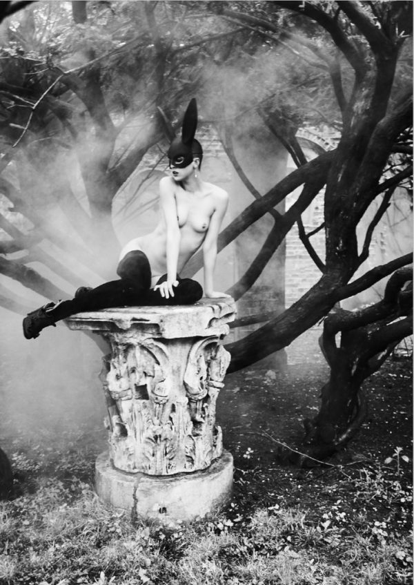 Bunny on a Pedestal by Ellen von Unwerth, Model in Bunnymask and stockings on broken column capital